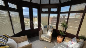 A sunroom with wicker furniture, large windows, and a view of the outside.