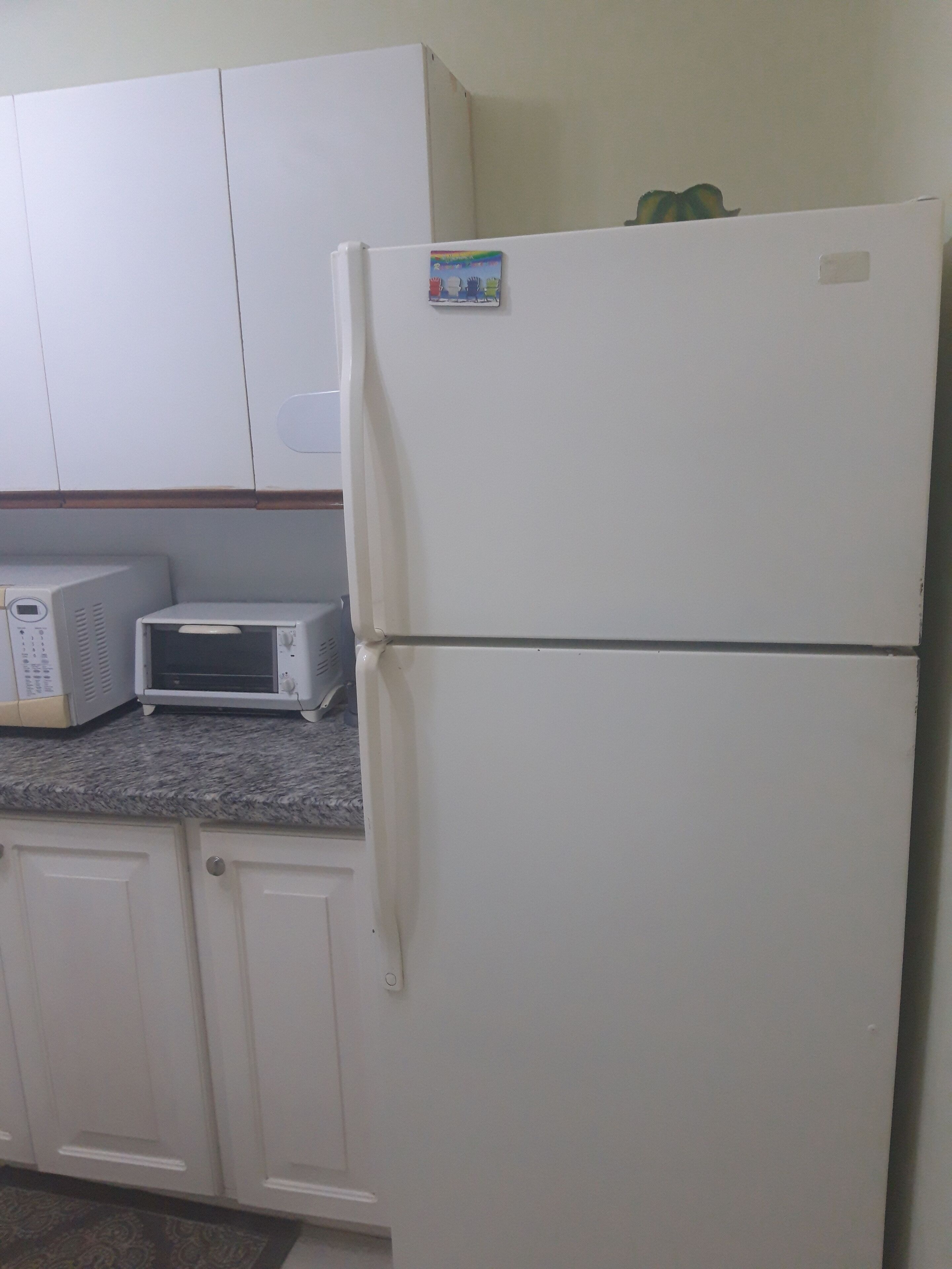 A kitchen with white cabinets, a microwave, and a refrigerator.