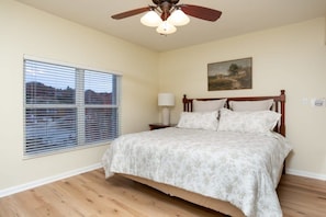 A bedroom with a bed, a ceiling fan, a window with blinds, and a painting on the wall. - Downtown, Riverfront PigeonForge (Pigeon Forge)