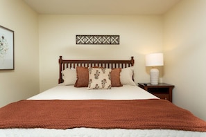 A neatly made bed with a brown blanket, a wooden headboard, and a decorative wall piece above it. - Downtown, Riverfront PigeonForge (Pigeon Forge)