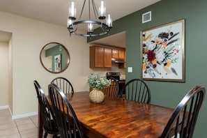 A dining area with a wooden table, chairs, a chandelier, a mirror, and a framed floral artwork on the wall. - Downtown, Riverfront PigeonForge (Pigeon Forge)