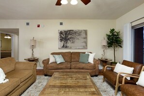A living room with a brown sofa, a coffee table, and a painting on the wall. - Downtown, Riverfront PigeonForge (Pigeon Forge)