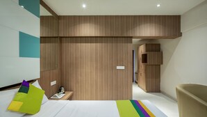 Una habitación de hotel moderna con una cama, una mesita de noche con un hervidor y un armario empotrado.