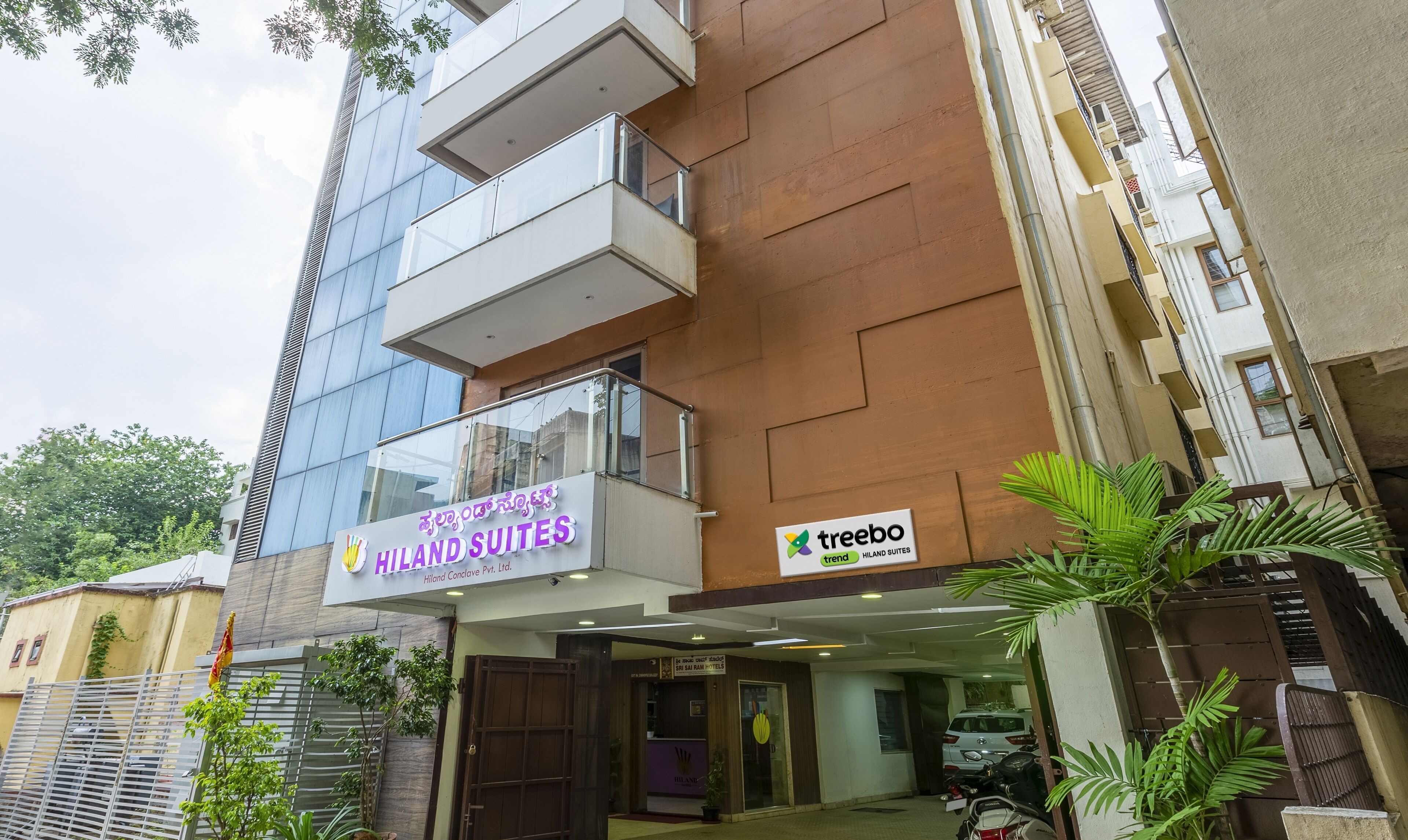 A hotel with a modern facade, balconies, and a visible entrance.