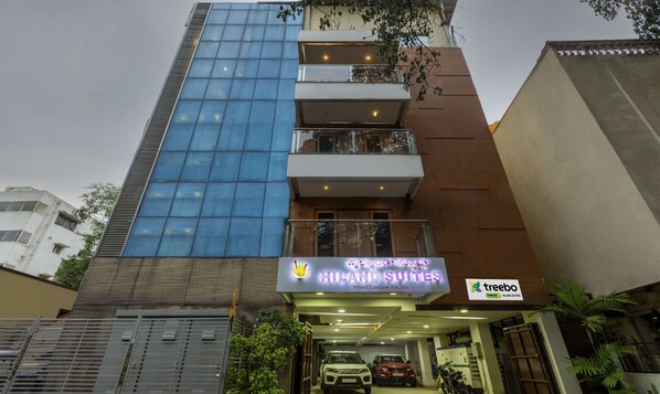 Un edificio de varios pisos con fachada de vidrio moderna y el letrero de Hiland Suites.
