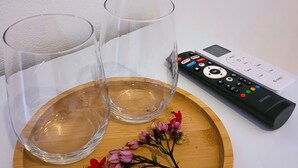 Two clear glasses on a wooden tray with a remote control beside them. - Pousada Vilarejo (Porto Seguro)