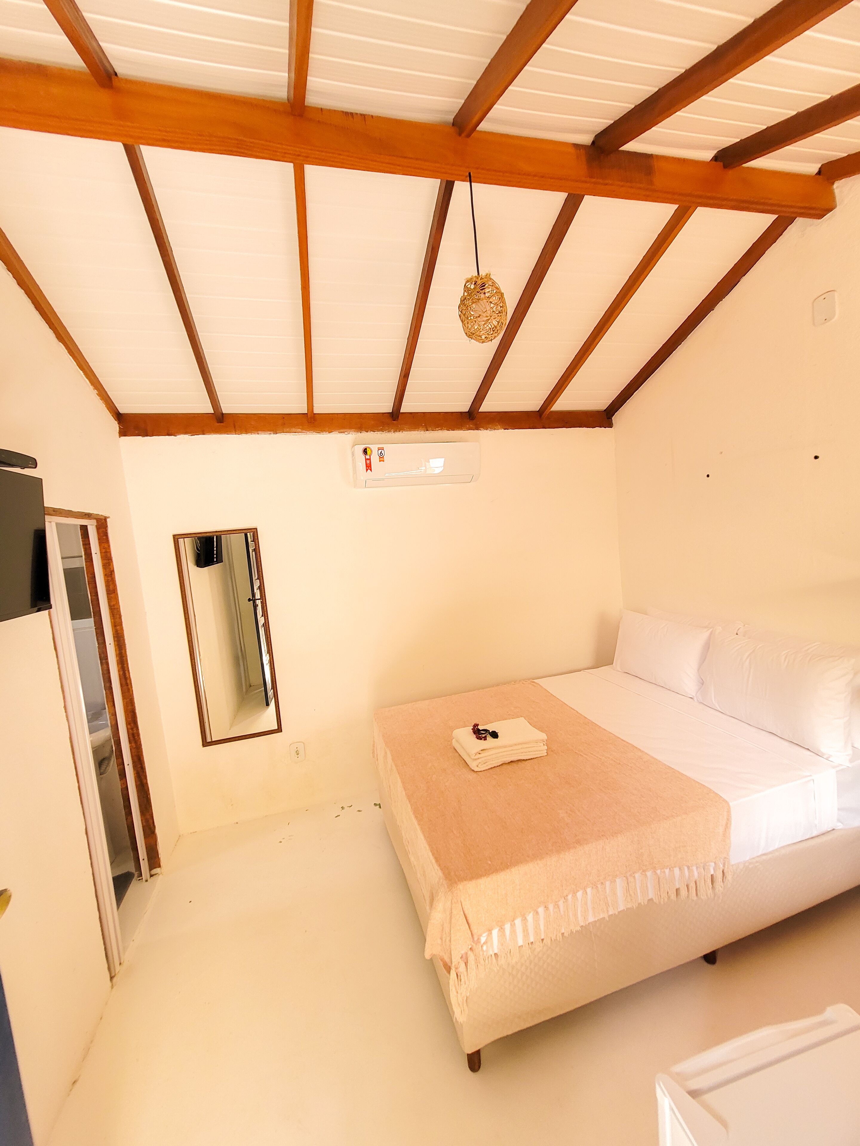 A bedroom with a bed, a mirror, and a ceiling fan.