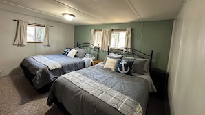 A bedroom with two beds, each with a headboard, a nightstand, a window with curtains, and a ceiling light.