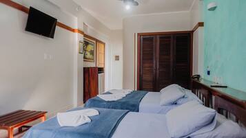 A hotel room with two beds, a television mounted on the wall, a ceiling fan, and a wooden door.