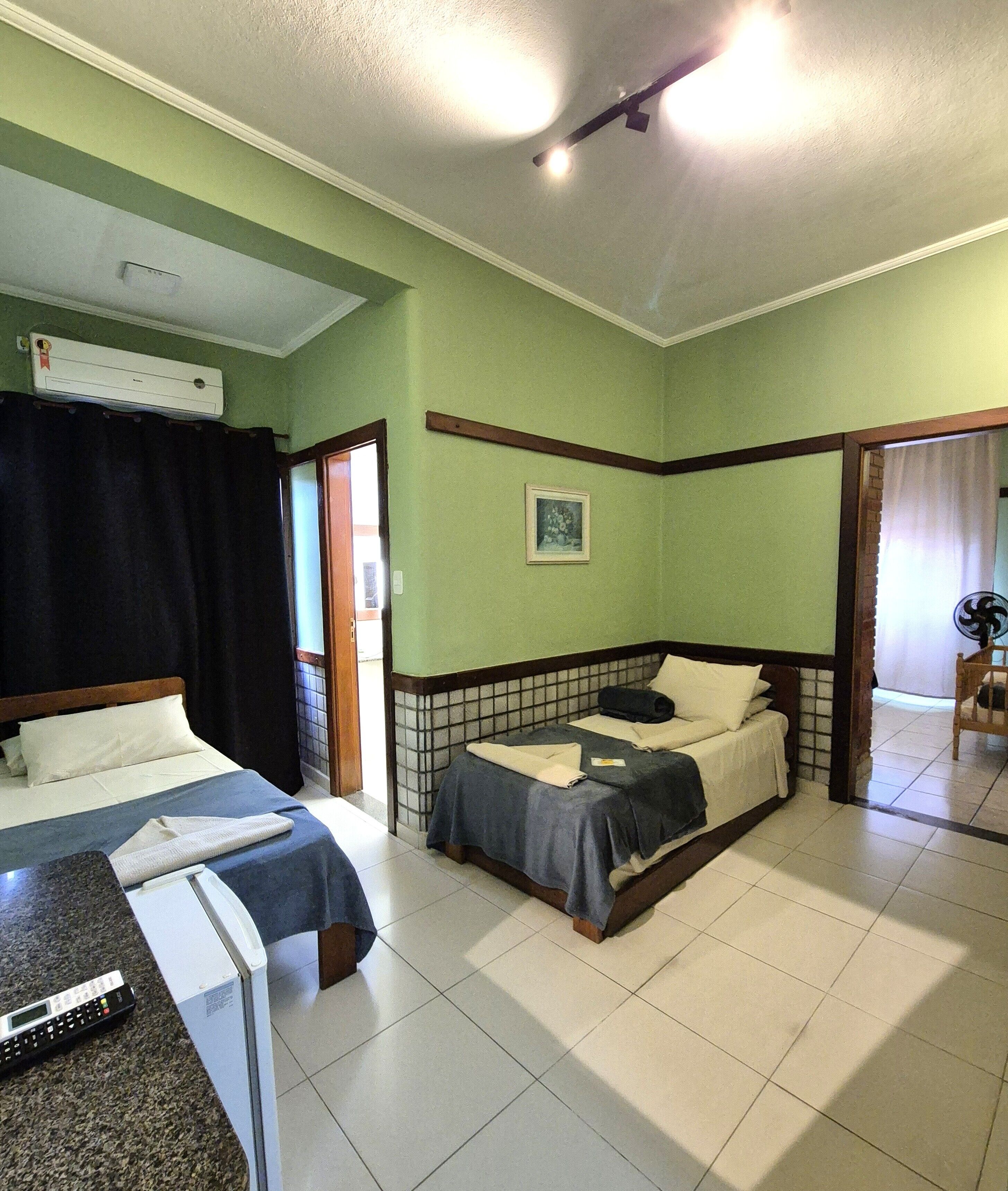 Una habitación de hotel con dos camas, un baño con ducha y una pequeña zona de estar.