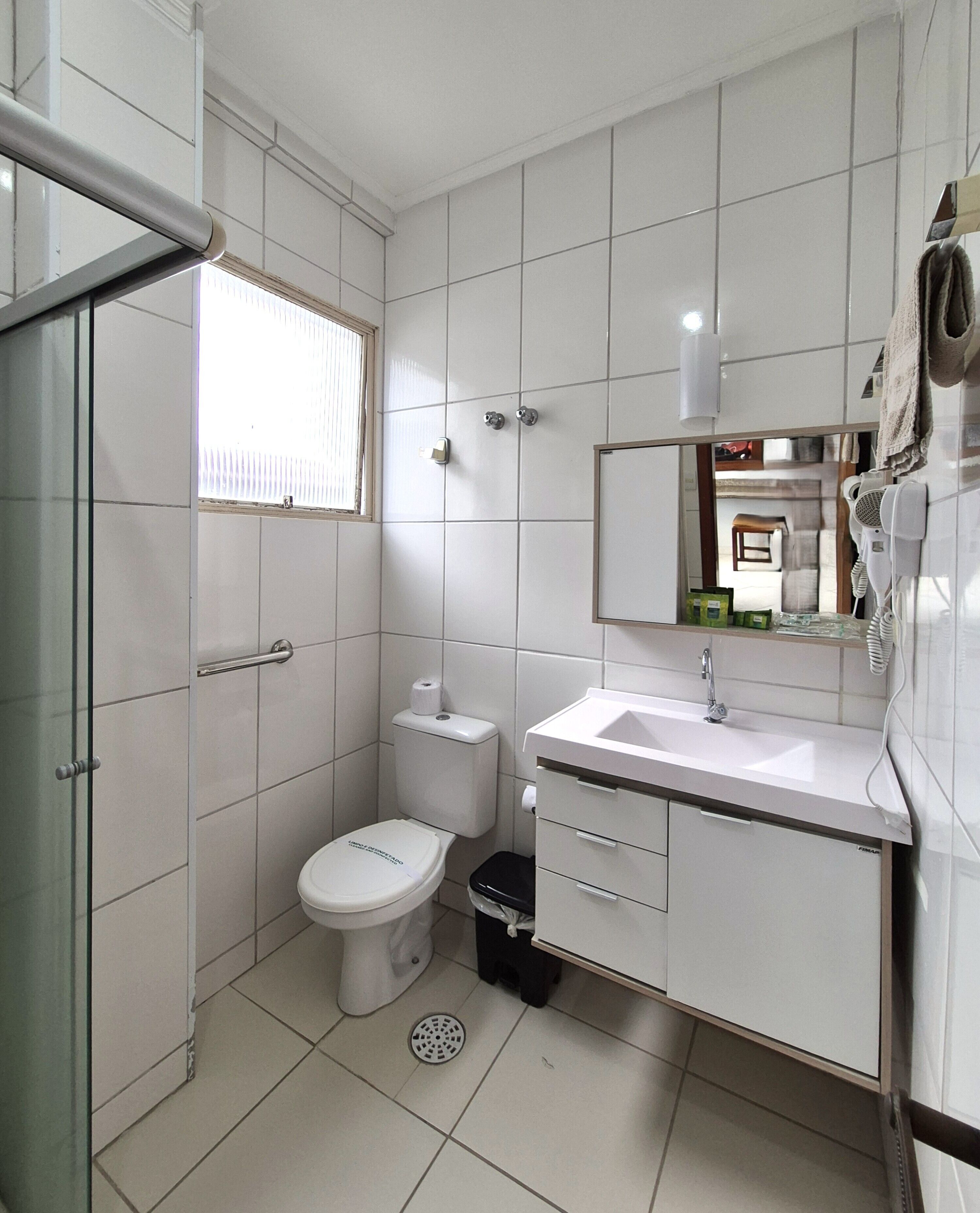 Un baño con inodoro, lavabo, espejo y ducha.