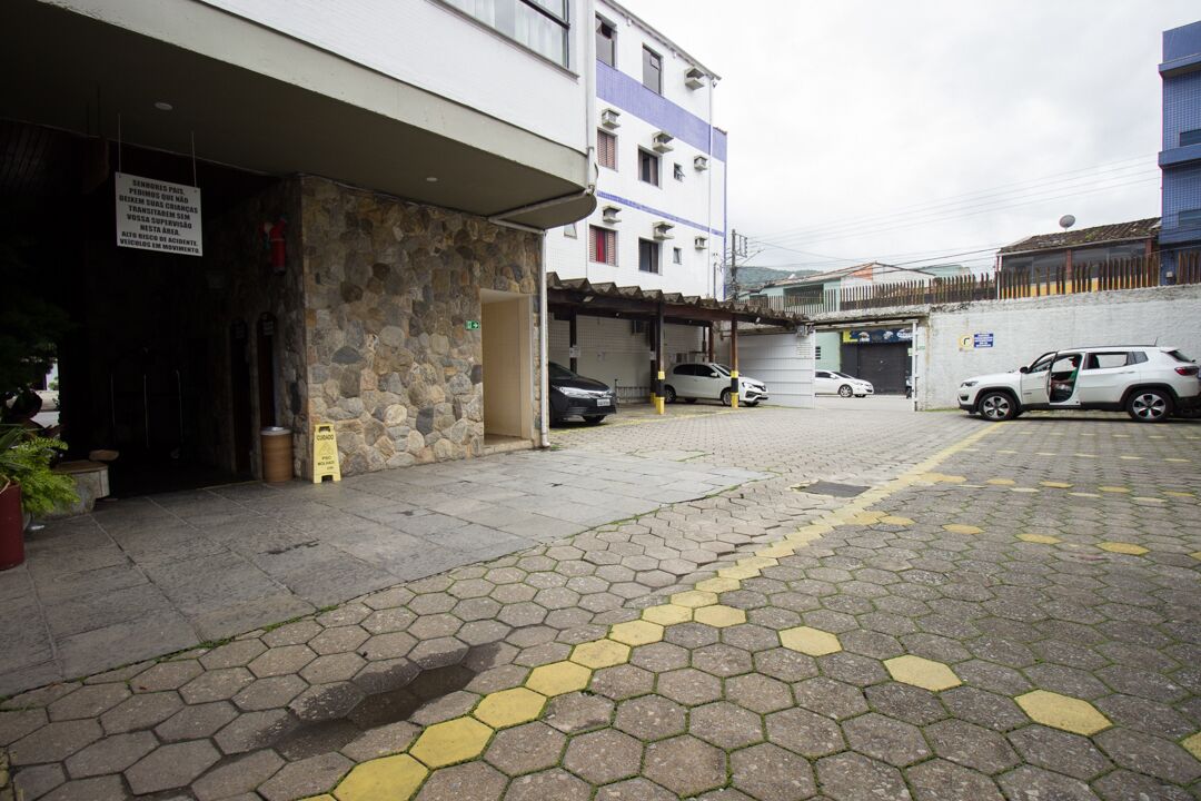 A parking area with hexagonal paving, a stone wall, and a building with multiple floors and balconies.