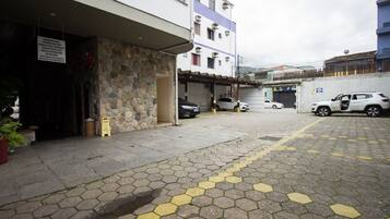 A parking area with hexagonal paving, a stone wall, and a building with multiple floors and balconies.