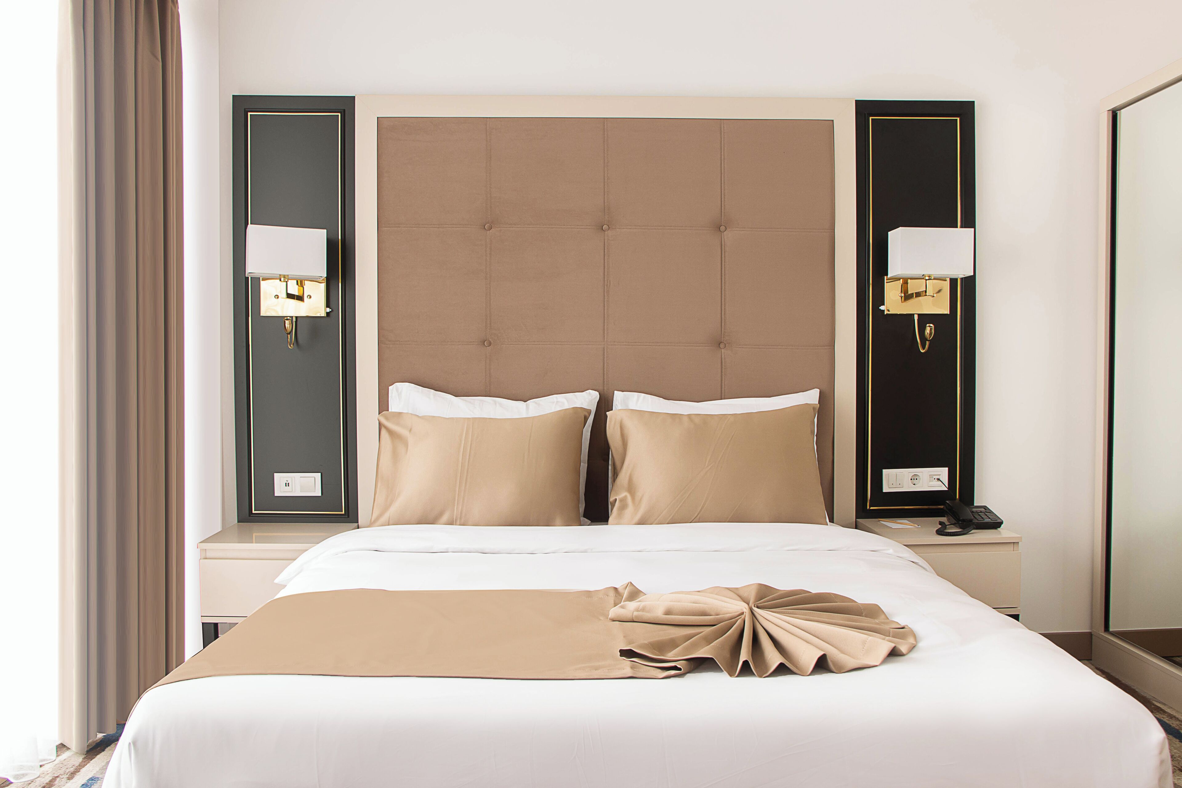 Una habitación de hotel con una cama grande, dos mesitas de noche y un espejo.