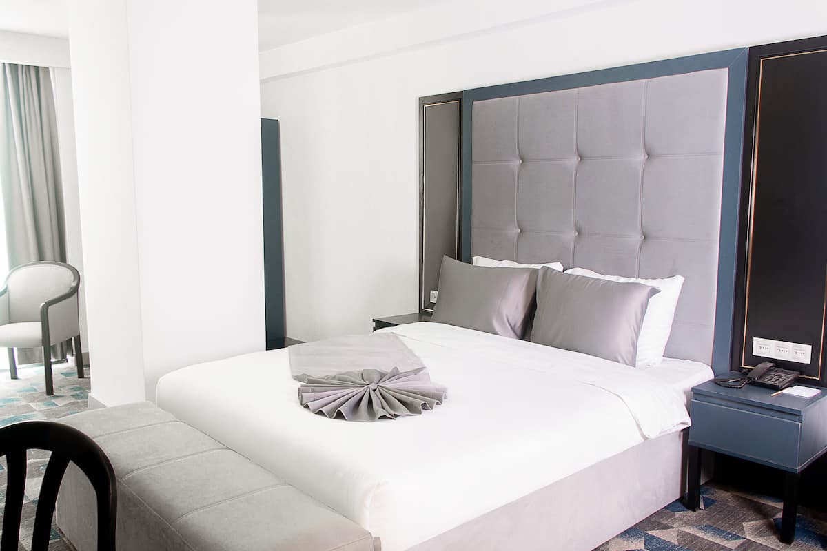 Quarto de hotel moderno com uma cama grande, uma mesa de cabeceira e uma cadeira.