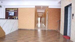 Ein Hotel-Rezeptionsbereich mit Marmor-Theke, einem Schild für das Jaya Ganga Arcade Lodge und einem Holzboden.