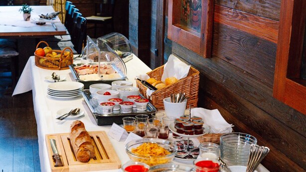 A buffet table with various food items, utensils, and wine glasses. - Bischofshof Braustuben (Regensburg)