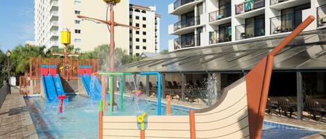 A swimming pool area with water slides and a children's play structure.