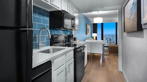 A modern kitchen with black appliances, white cabinets, and a blue backsplash.