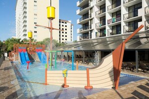 A swimming pool area with water slides and a children's play structure.