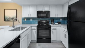 A modern kitchen with white cabinets, a black refrigerator, a black stove, and a microwave. - Seaside Splendor: 2nd Floor Two Bedroom Condo (Myrtle Beach)