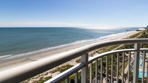 Blick auf einen Strand vom Balkon aus, mit Pool und Liegebereich.