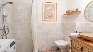 Et moderne badeværelse med bruser, toilet og en trækommode med vask.
