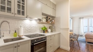 Et moderne køkken med indbygget ovn, stålvask og bordplade med en plante og køkkenredskaber.
