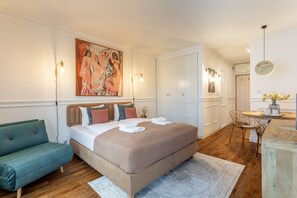 A bedroom with a large bed, a green sofa, a painting on the wall, and a dining area with a table and chairs. - Ferienwohnung am Meer, Urlaub auf der Insel Usedom, Apartment Amelia (Świnoujście)
