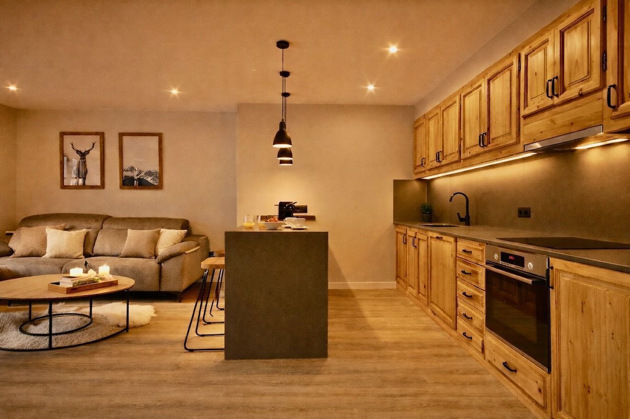 Een moderne keuken met houten kasten, een centraal eiland en een zithoek met een bank en salontafel.