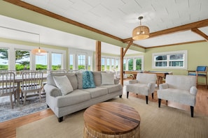 A spacious living room with a sofa, armchairs, a coffee table, and a pool table.
