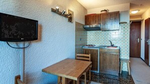 Une cuisine compacte avec une table et des chaises en bois, une cuisinière intégrée et un pare-feu en carreaux.