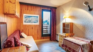Une pièce confortable avec un lit en bois, une petite table, une lampe et une fenêtre avec des rideaux.