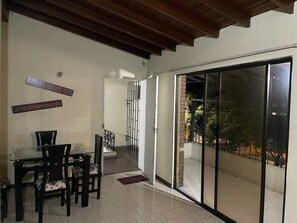 A dining area with a glass table and chairs, a sliding glass door leading to a balcony, and a sign on the wall. - Friends Gather Hostal (Medellín)