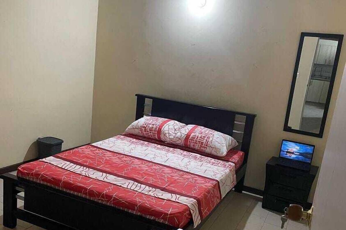 A bedroom with a bed, a nightstand, a TV, and a mirror.