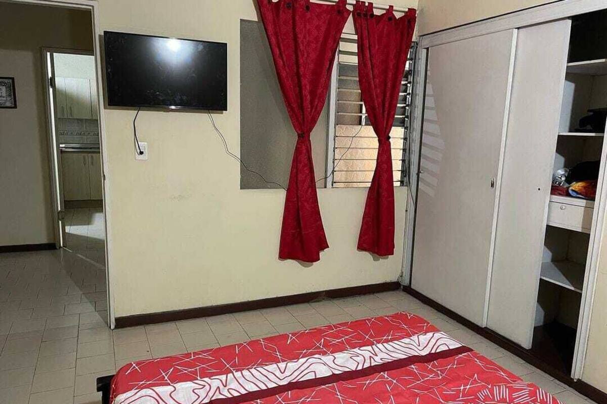 A bedroom with a bed, a TV mounted on the wall, and a wardrobe.