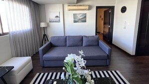 Una sala de estar moderna con un sofá gris, un tapete a rayas negras y blancas, y flores blancas sobre una mesa negra.