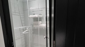 Un vestidor amplio con estantes y espacio para colgar, piso de madera y puerta de vidrio.