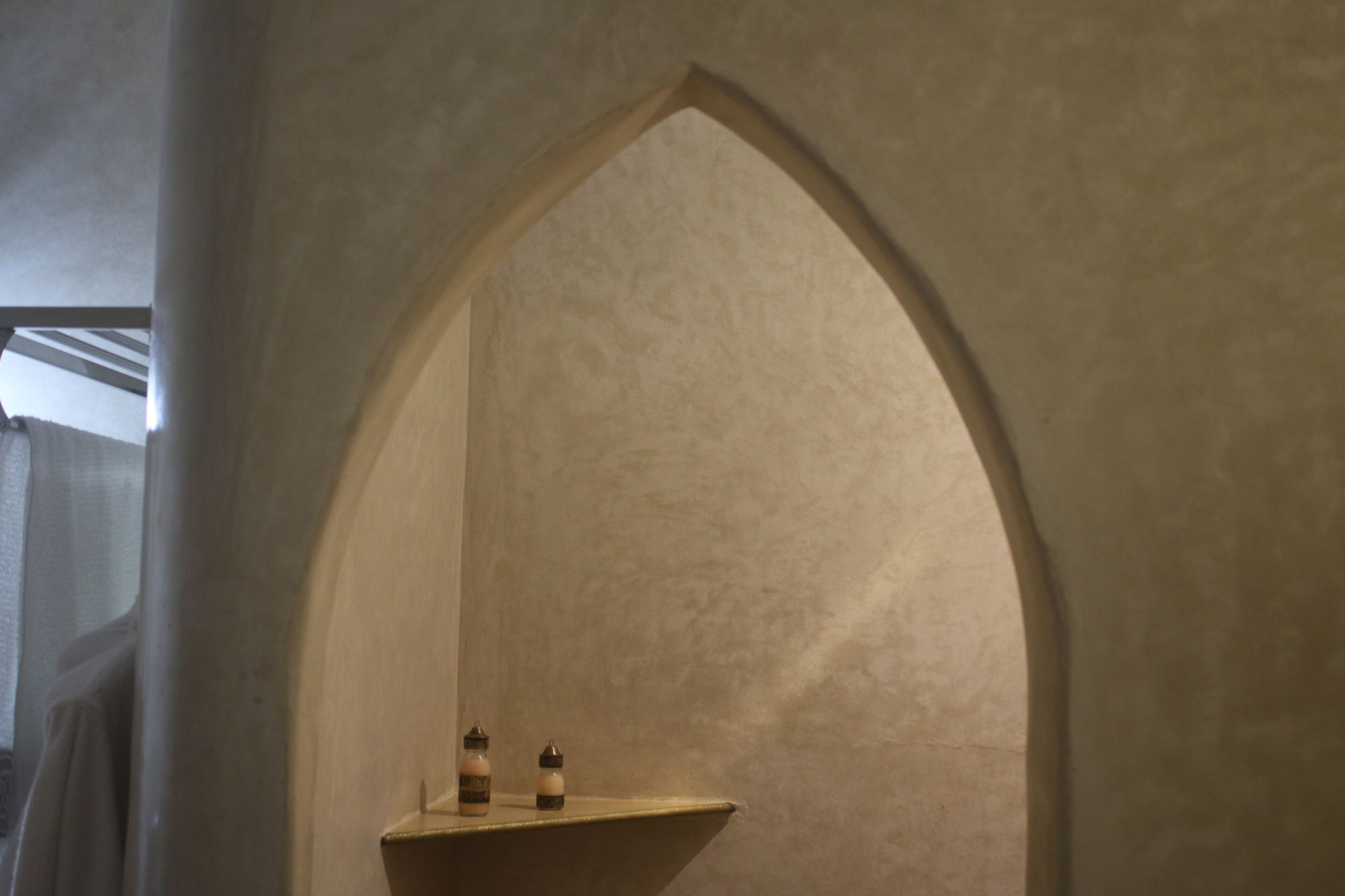 A narrow, arched alcove with a shelf holding two bottles.