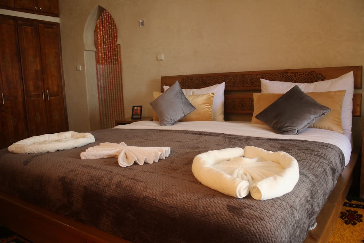 Een hotelkamer met een groot bed, een houten hoofdbord en meerdere kussens.