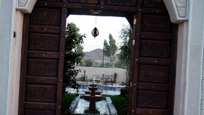 Une porte d’entrée en bois, agrémentée d’un paillasson et d’un tapis d’entrée sur lequel est inscrit le texte « IMIQRAN WELCOME ».