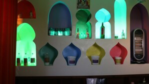 Un mur orné de fenêtres de formes variées, chacune contenant différents objets, comme des bouteilles et un radiateur.