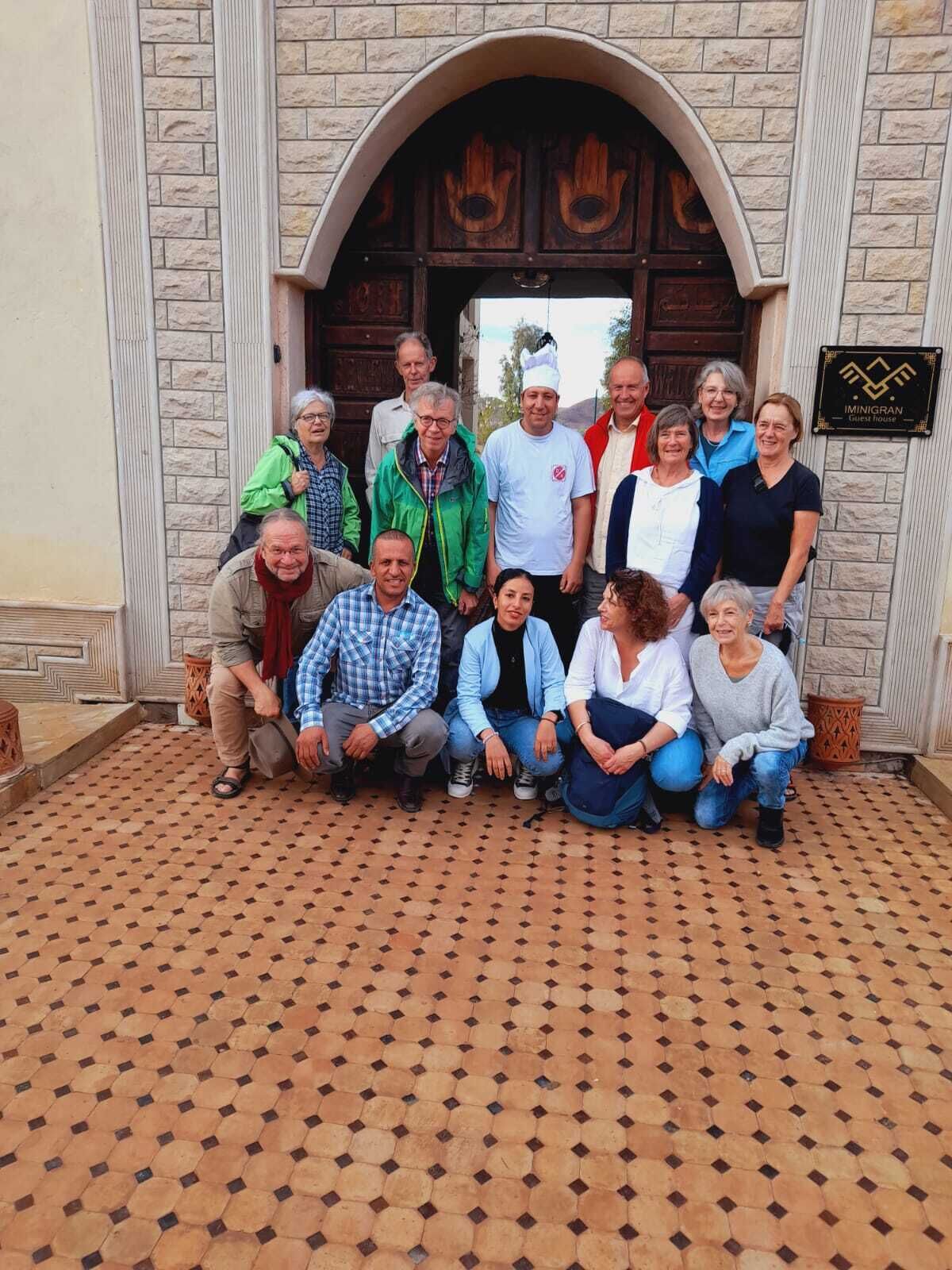 A group of people posing in front of a building with a stone facade and a wooden door.