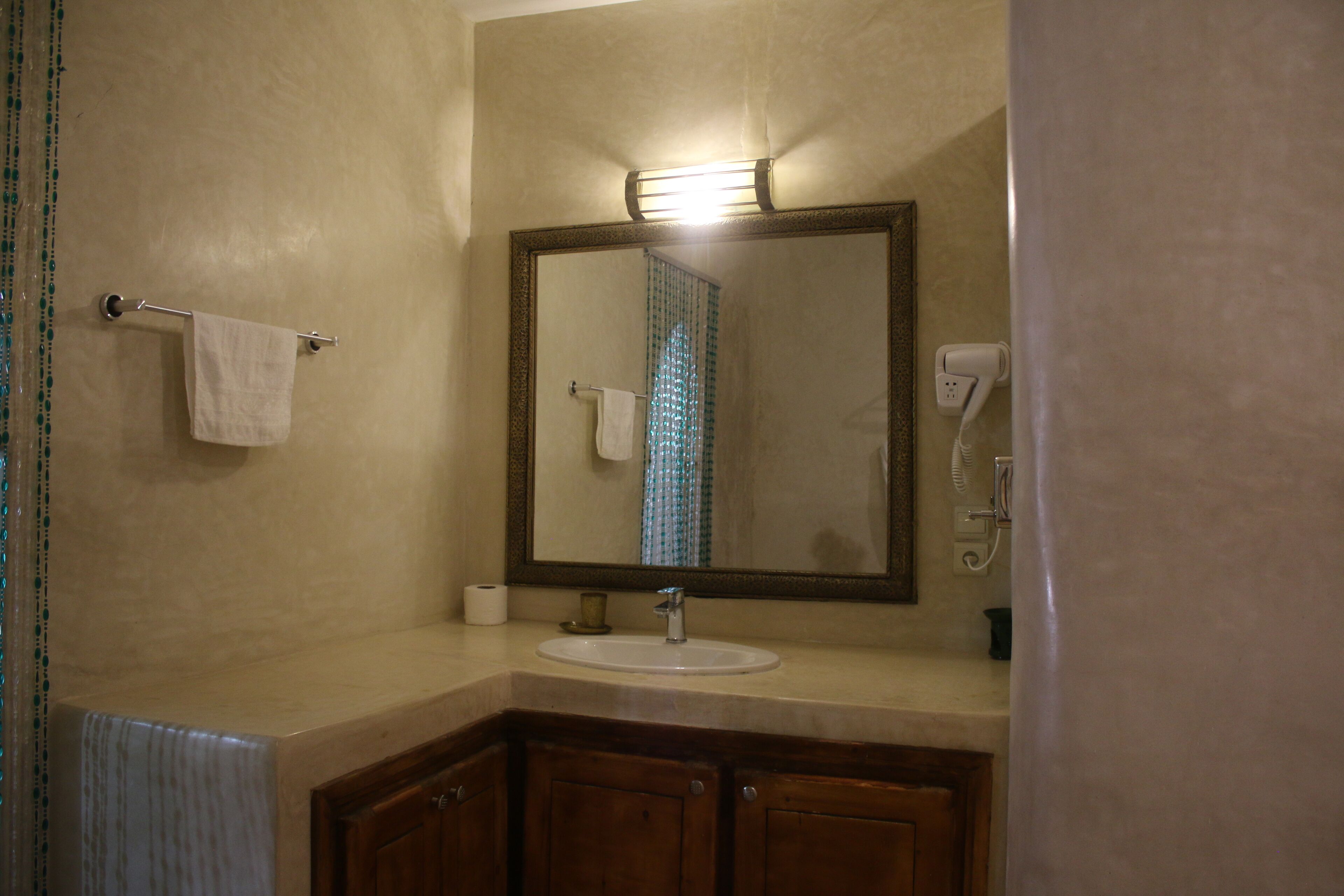 Un baño con lavamanos, espejo, toallero y cortina de ducha.