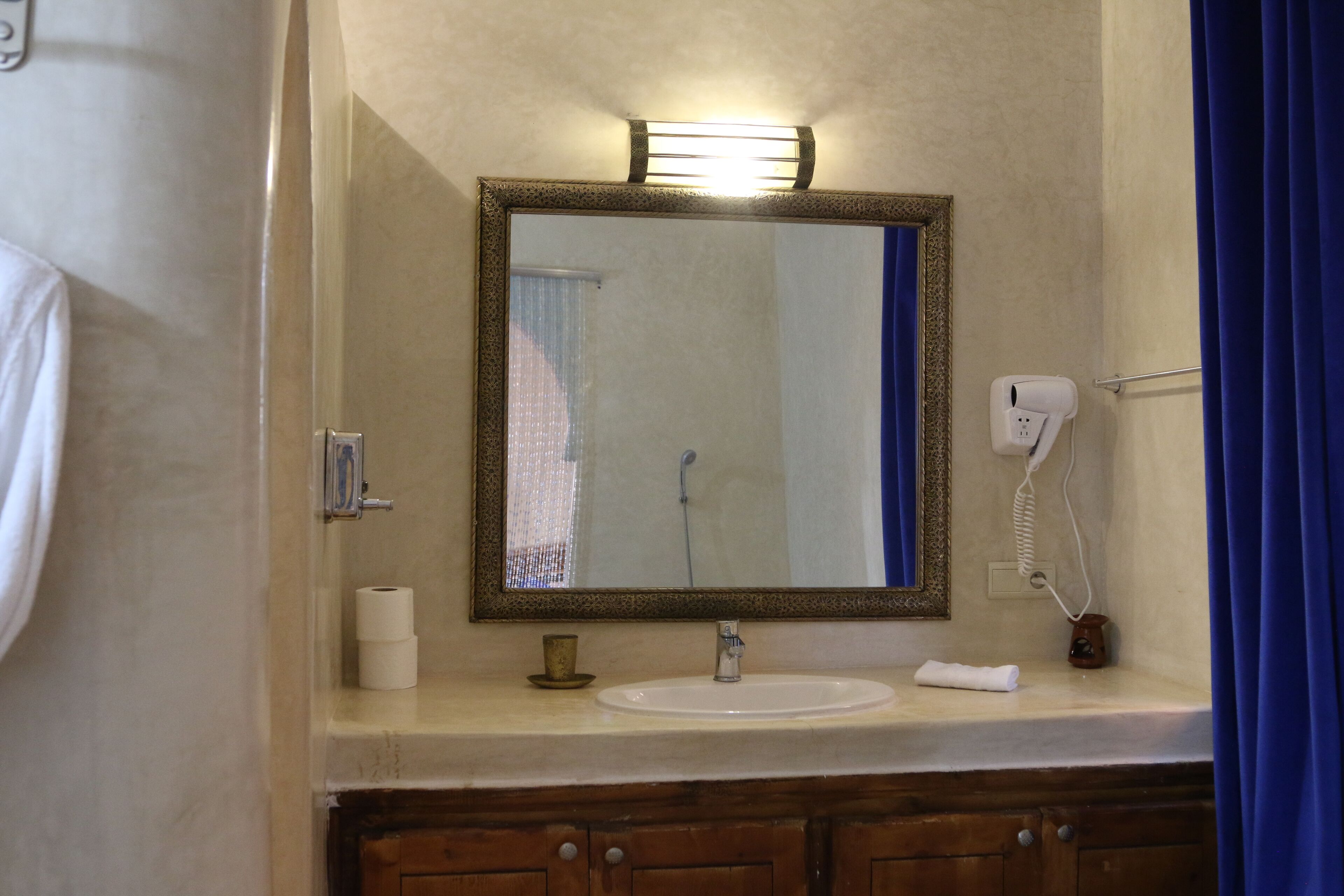 A bathroom with a sink, mirror, and a hairdryer on the counter.