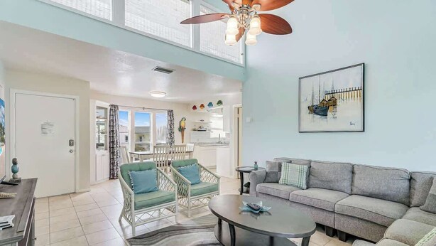A spacious living area with a ceiling fan, a sofa, a coffee table, and a dining area with chairs.