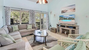 A living room with a sofa, a coffee table, a TV, and a ceiling fan.