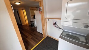 A laundry room with a Whirlpool washer and dryer, wooden flooring, and a visible electrical outlet.