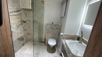 A bathroom with a glass-enclosed shower, a toilet, and a sink.