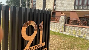 Señal que indica '91 IYIOCHA ROAD WINPHER BY AA91', con un edificio moderno al fondo.